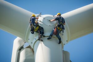 Two technicians in safety harnesses and hard hats performing maintenance on a wind turbine nacelle, highlighting the use of non-sparking, non-magnetic tools for renewable energy sector safety.
